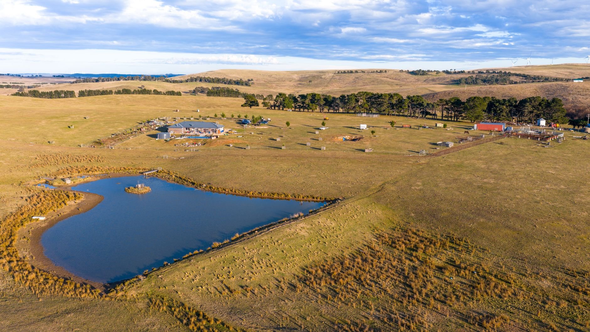Scenic aerial view of a rural farm landscape with a pond, buildings, and open fields.