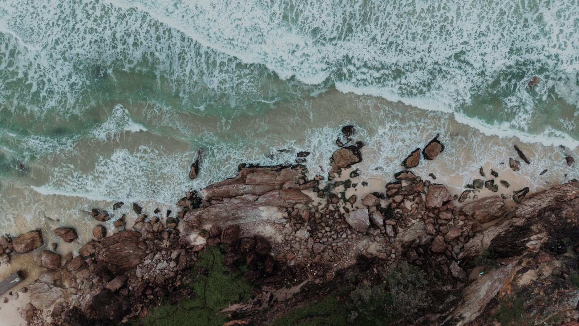 Dramatic aerial view of waves crashing on the rocky shoreline of the Gold Coast, Australia.
